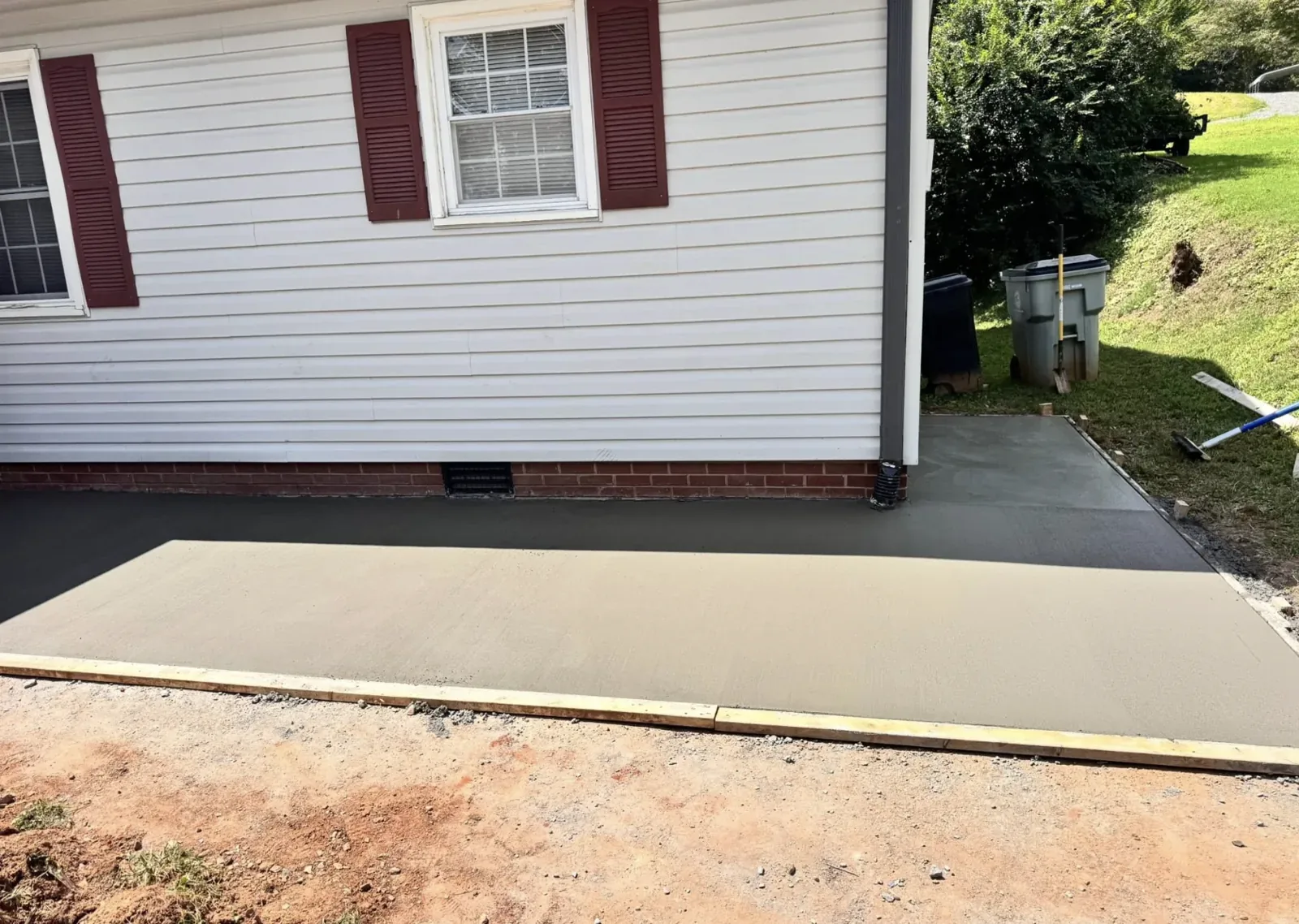 A concrete parking pad poured beside a house &mdash; Little Acres Grading