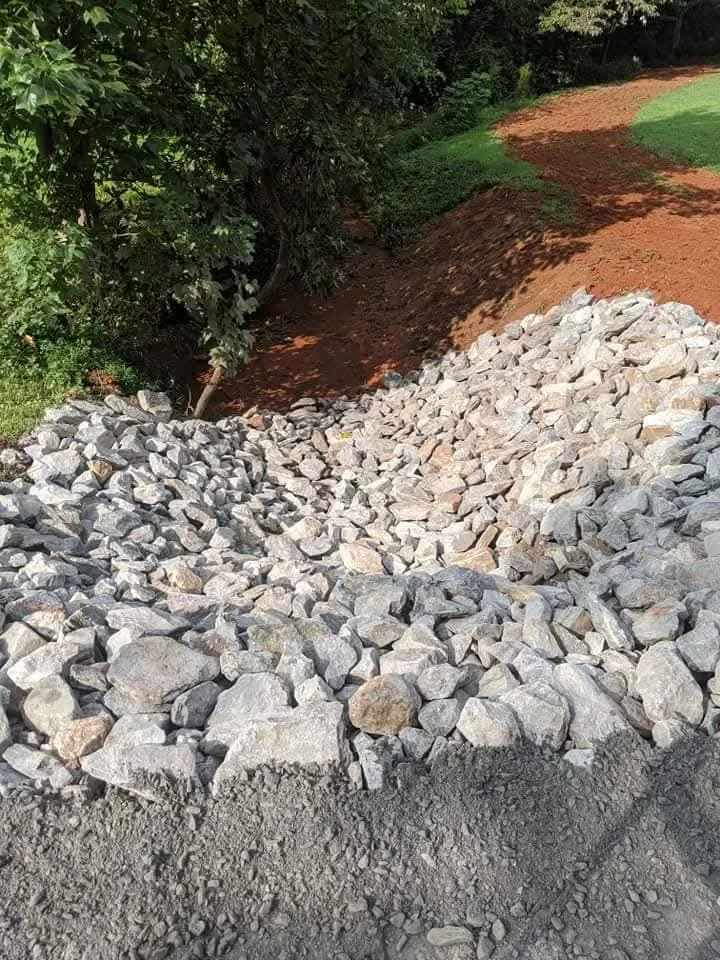 A stone outlet built into a hillside to slow and spread stormwater &mdash; Little Acres Grading