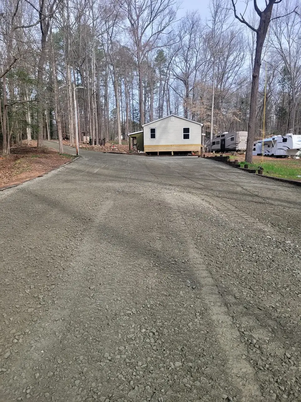 A new gravel drive graded and stoned up to a home set back in the trees — Little Acres Grading