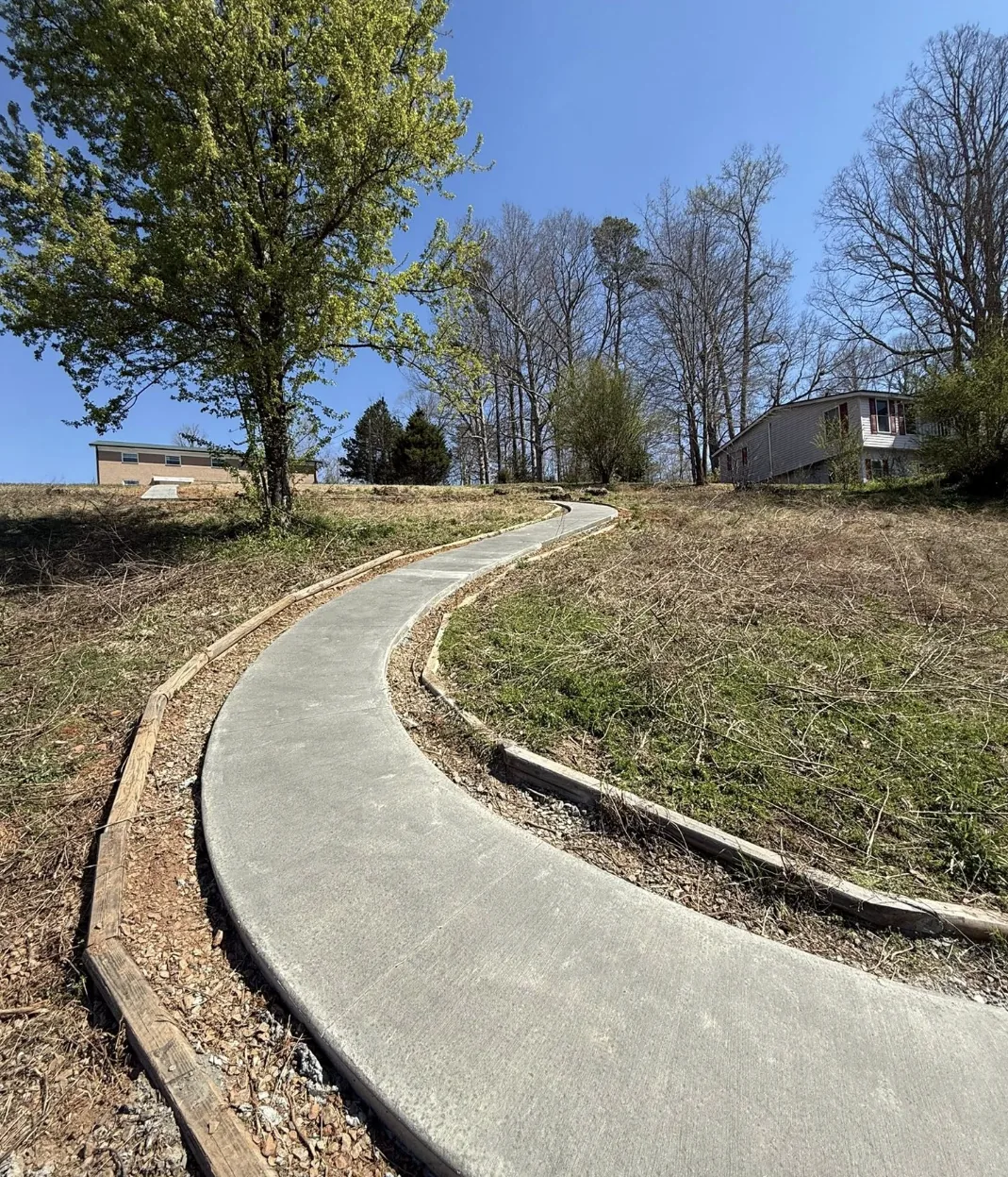 Freshly poured curved concrete driveway on a graded slope by Platinum Construction & Crane