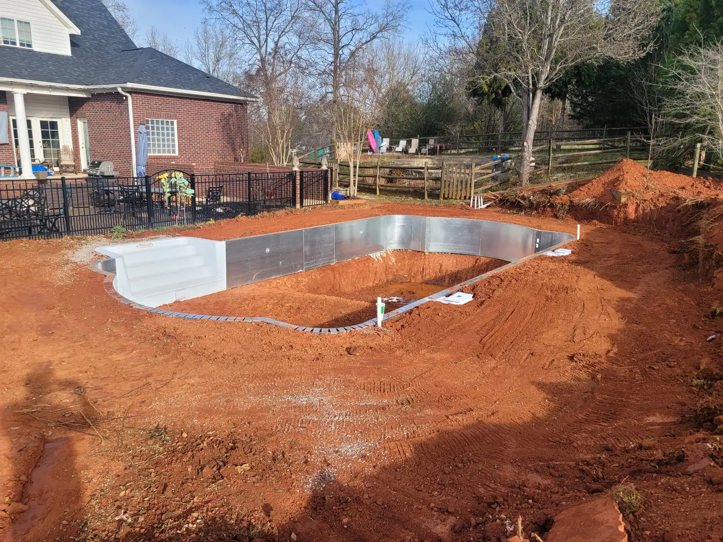 A pool dug and walled in behind a brick home with the spoil graded off &mdash; Little Acres Grading