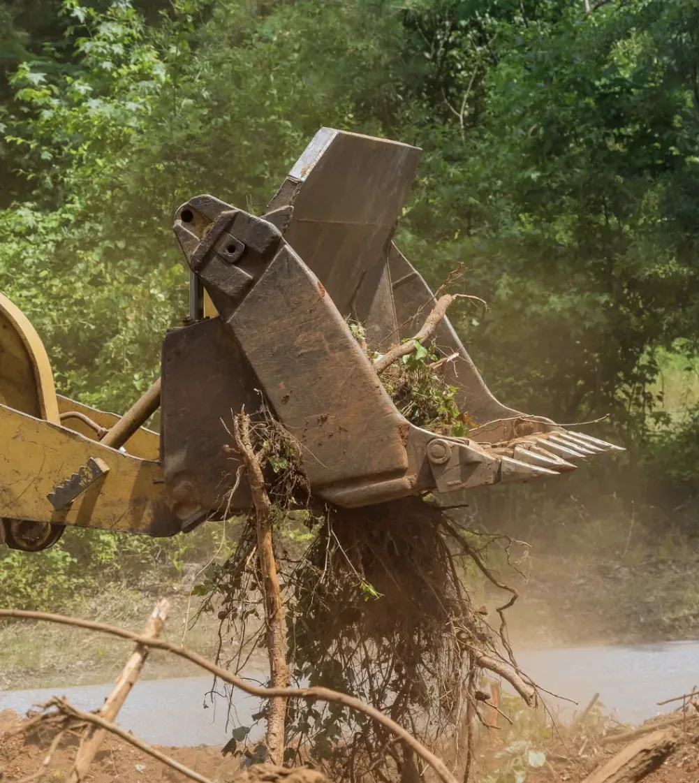 A grapple attachment lifting a stump clear of the ground — Little Acres Grading